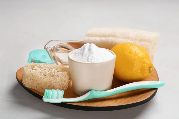 Bowl with baking soda, lemon and cleaning items on plate