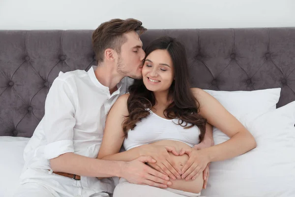 남편과 침대에서 손으로 하트를 보여주는 임신한 — 스톡 사진