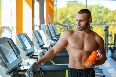 Spor salonunda treadmill sallamak protein ile atletik erkek portresi