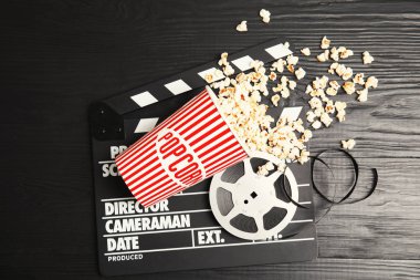 Lezzetli patlamış mısır, film makaraları ve Klaket ahşap arka plan, üstten görünüm üzerinde. Sinema snack