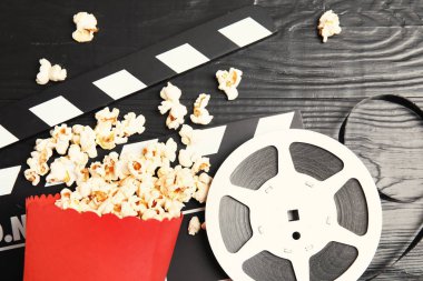 Lezzetli patlamış mısır, film makaraları ve Klaket ahşap arka plan, üstten görünüm üzerinde. Sinema snack