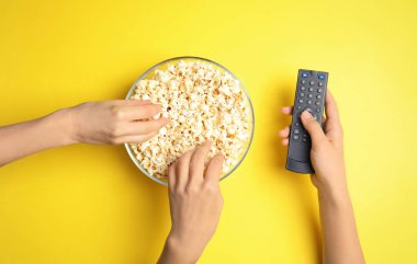 Tv Uzaktan kadınlarla en iyi görünüm renk arka plan üzerinde patlamış mısır yemek. Sinema izliyor