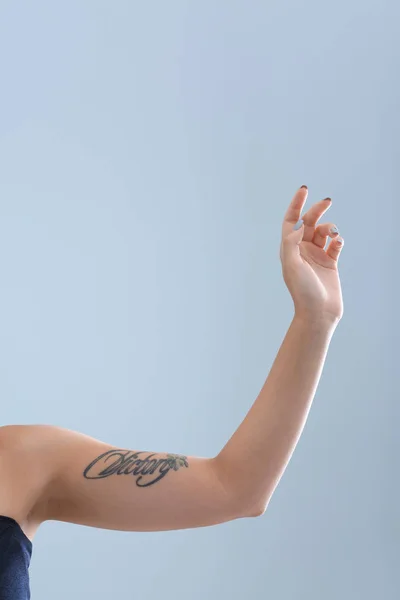 Female arm with tattoo on color background
