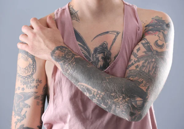 Young man with stylish tattoos on white background