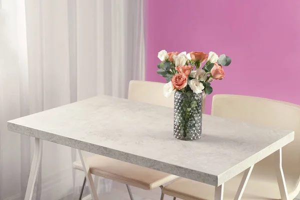 Vase with beautiful flowers as element of interior design on table in room. Space for text