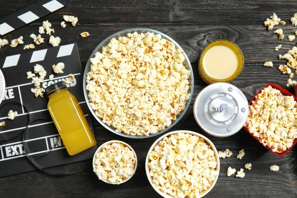 Flat lay composition with popcorn, cinema clapperboard and drinks on wooden background