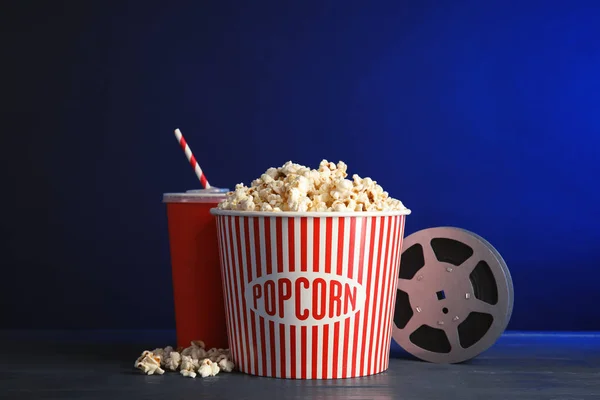 Composition with popcorn and cinema reel on table against color background