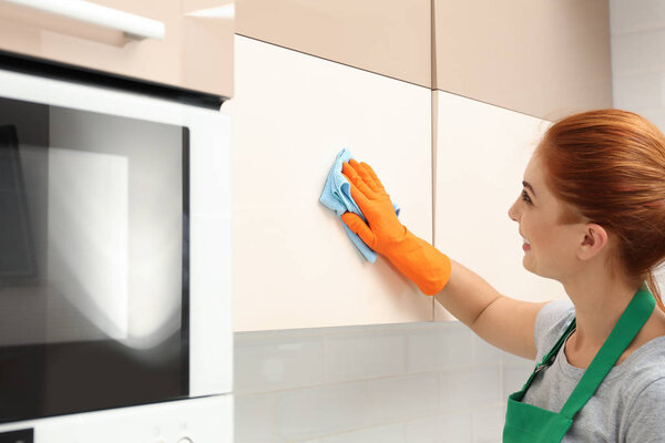Woman cleaning kitchen with rag, indoors