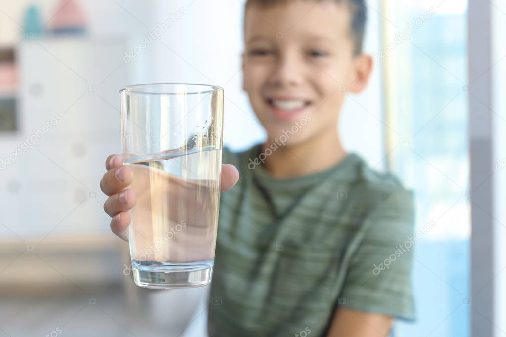 Little boy holding glass of fresh water at home, closeup