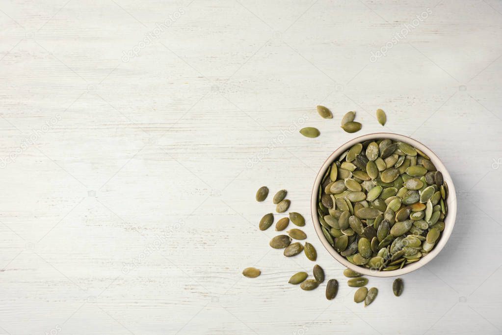Shelled raw pumpkin seeds on wooden background, top view. Space for text