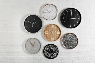 Farklı analog saatler beyaz duvarda asılı. Günün saati