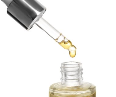 Beyaz arka plan üzerinde cam şişe içine pipet uçucu yağ damlama