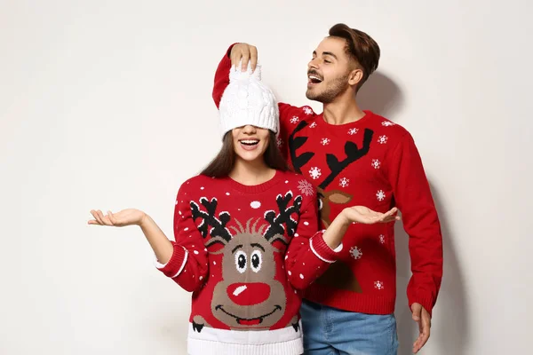 白い背景の上のクリスマス セーターで若いカップル — ストック写真