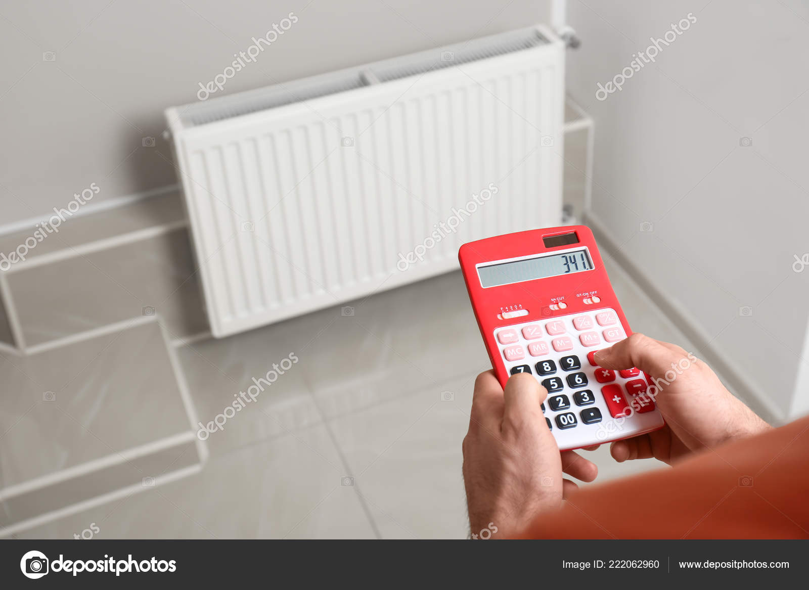 Man Holding Calculator Heating Radiator Indoors Stock Photo by