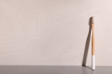 Bambu diş fırçası tabloda gri bir arka plana dayanır. Metin için yer