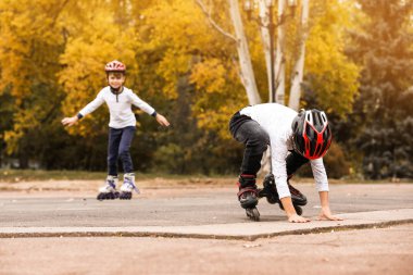 Happy children roller skating in autumn park clipart