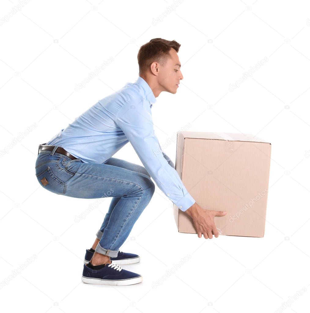 Full length portrait of young man lifting heavy cardboard box on white background. Posture concept