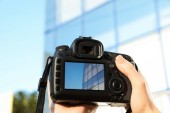 Fotografek drží profesionální fotoaparát s obrázkem na obrazovce venku, closeup