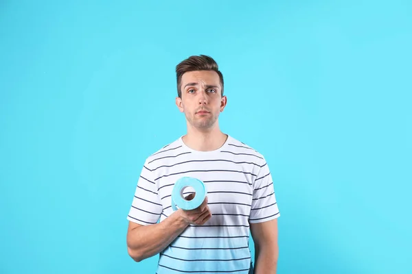 Young Man Holding Toilet Paper Roll Color Background — Stock Photo, Image