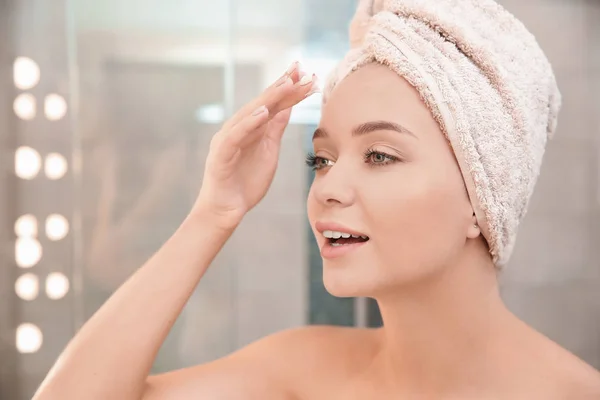 Hermosa Mujer Con Toalla Cabeza Aplicando Crema Facial Baño — Foto de Stock