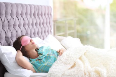 Genç güzel kadın maskesi evde yatakta uyuyor. Sabah erken