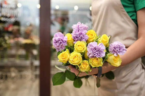 Female florist holding beautiful bouquet in flower shop, closeup