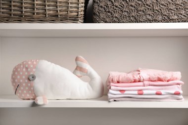 Yığılmış bebek giysileri ve raf peluş oyuncak
