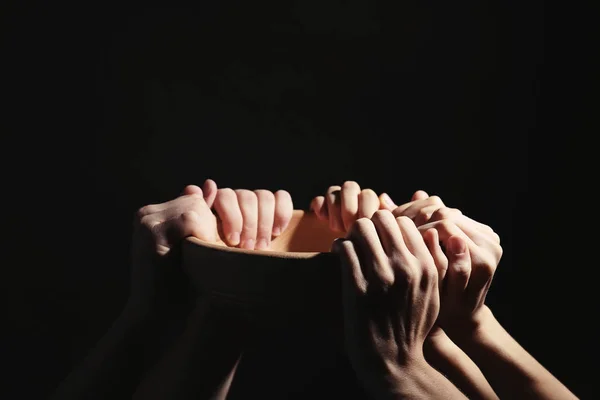 Poor people holding bowl on dark background, closeup