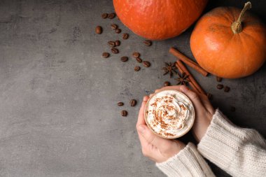 Fincan lezzetli kabak spice latte gri tablo, düz metin için yer ile yatıyordu tutan kadın