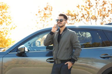 Modern araba, açık havada yakınındaki telefonda konuşan genç adam