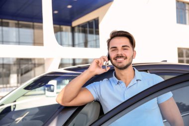 Modern araba, açık havada yakınındaki telefonda konuşan genç adam