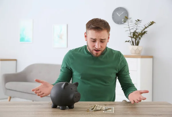 Emotionele Jongeman Met Spaarvarken Geld Aan Tafel Binnenshuis — Stockfoto