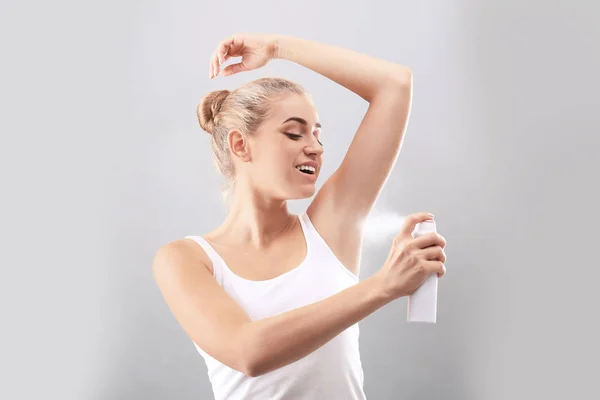 Mujer Joven Usando Desodorante Sobre Fondo Gris —  Fotos de Stock