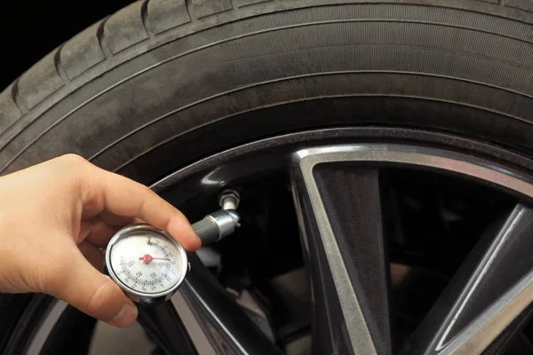 Man measuring car tire pressure with air gauge, closeup. Safety control
