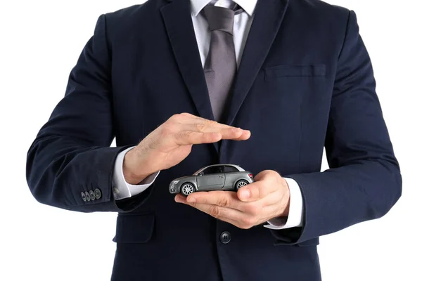 白い背景に クローズ アップでおもちゃの車を保持している男性の保険エージェント — ストック写真