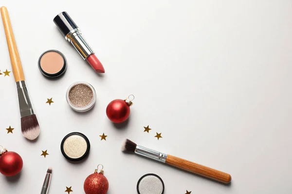 Flat lay composition with makeup products and Christmas decor on white background. Space for text