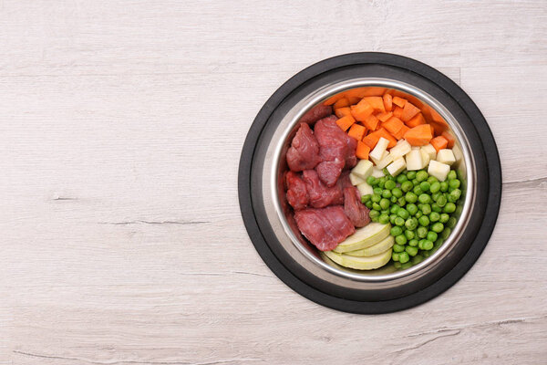 Bowl with organic dog food on light background, top view. Space for text