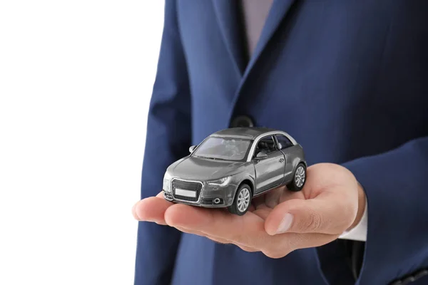 白い背景に クローズ アップでおもちゃの車を保持している保険代理店 — ストック写真