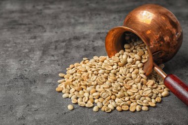 Yeşil kahve çekirdekleri ve gri arka plan üzerinde metin için yer ile devrilmiş jezve