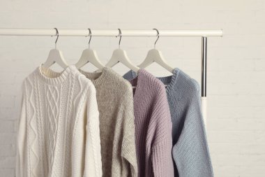 Sıcak kazak raf beyaz tuğla duvara asılı topluluğu