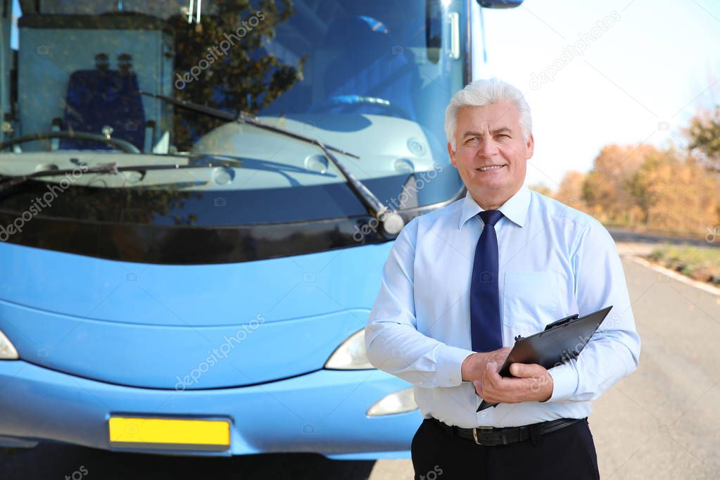 Professional driver with clipboard near bus. Passenger transportation