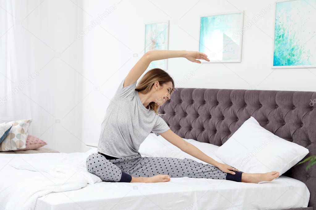Young beautiful woman doing exercise on bed at home. Morning fitness