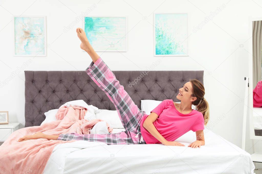 Young beautiful woman doing exercise on bed at home. Morning fitness