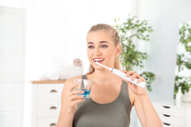 Diş fırçalama ve diş macunu ile cam banyoda tutan kadın