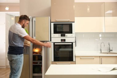 Kağıt torba yakınındaki evde buzdolabı taze gıda ile genç adam