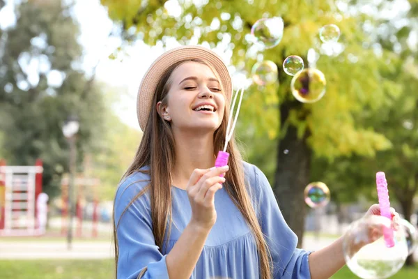 公園でシャボン玉を吹く若い女性 — ストック写真