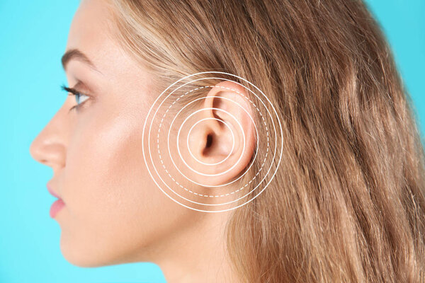 Young woman with symptom of hearing loss on color background. Medical test