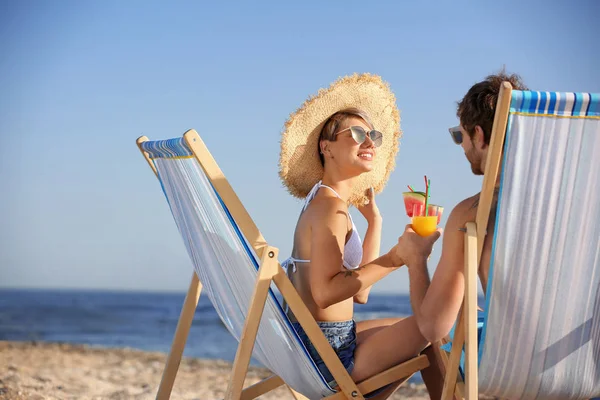 海岸でビーチチェアでカクテルと若いカップルします — ストック写真