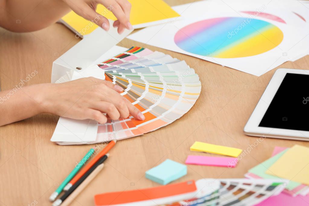 Designer with paint color palette samples at table, closeup