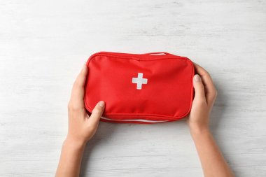 Ahşap arka planda ilk yardım çantasını tutan kadın.